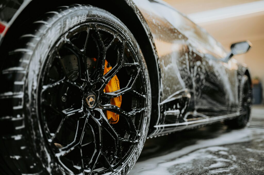pexels photo 14231678 14231678 Detailed close-up of a luxury car wheel covered in soap suds during a professional car wash.