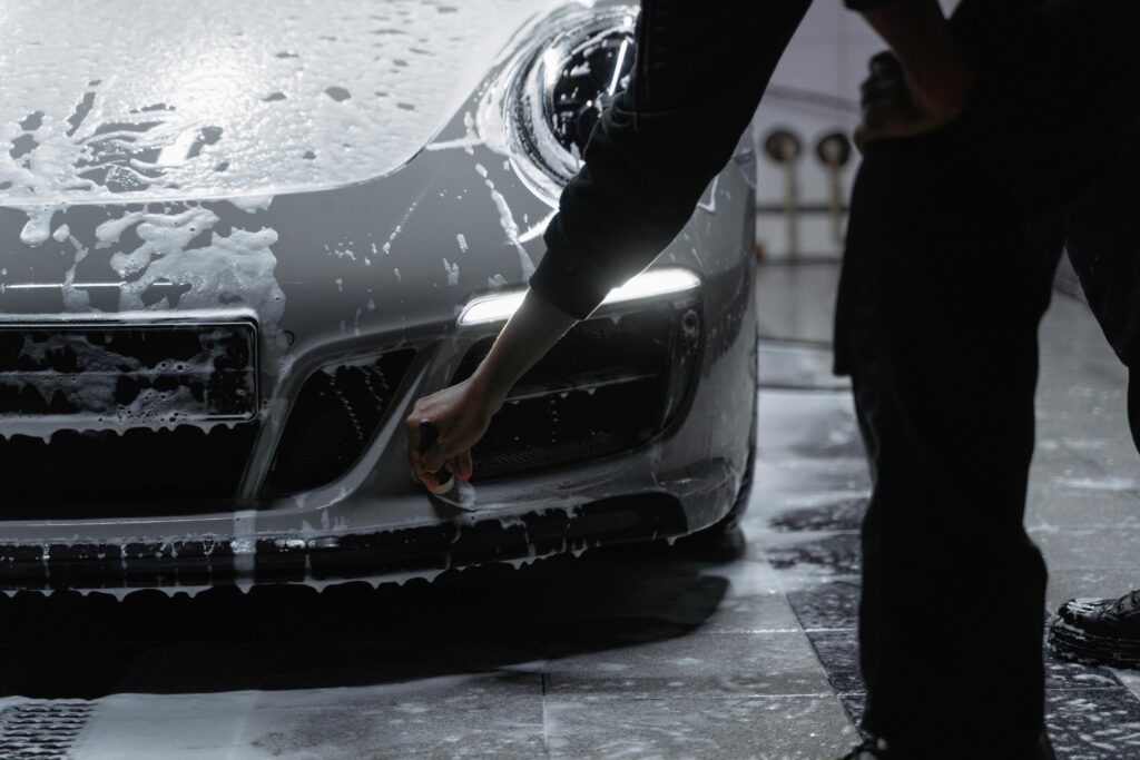 A close-up view of a car being meticulously washed with soap in a garage setting, emphasizing cleanliness and care.