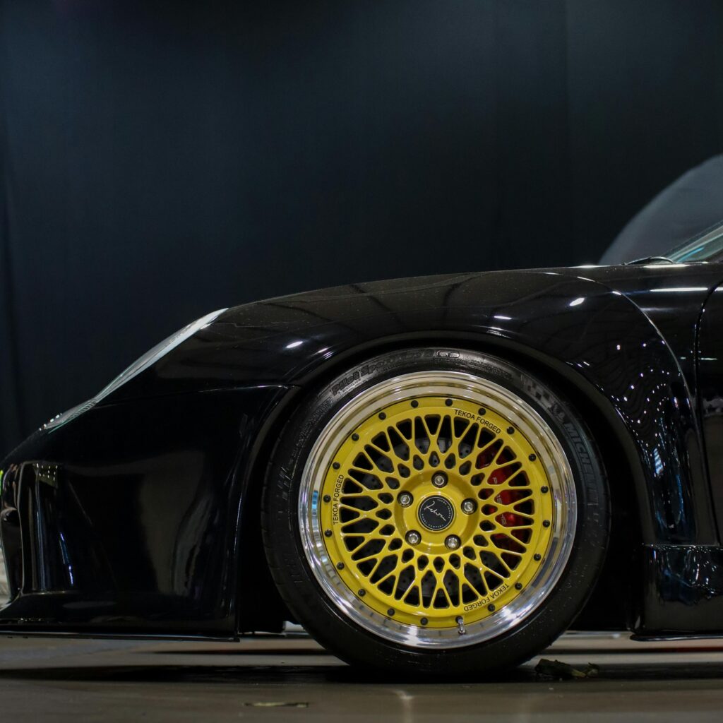 Close-up of a sleek black sports car featuring a stylish gold alloy wheel.
