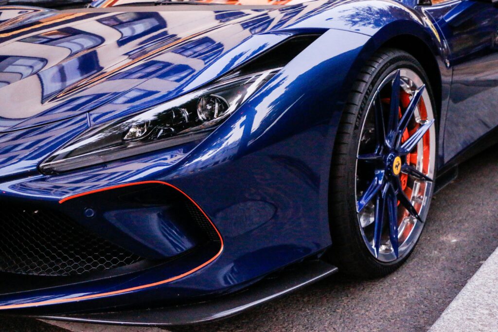 Close-up of a sleek blue sports car with shiny reflective surface and unique wheel design.